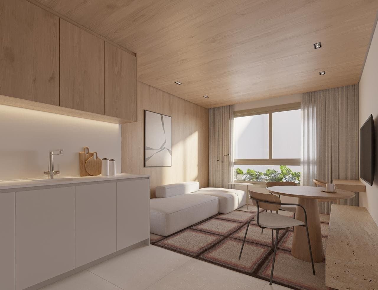 Studio compacto do Garcya Praia Studios com cozinha linear, armários em madeira, sofá modular branco, mesa de jantar redonda, TV na parede e teto revestido em madeira.